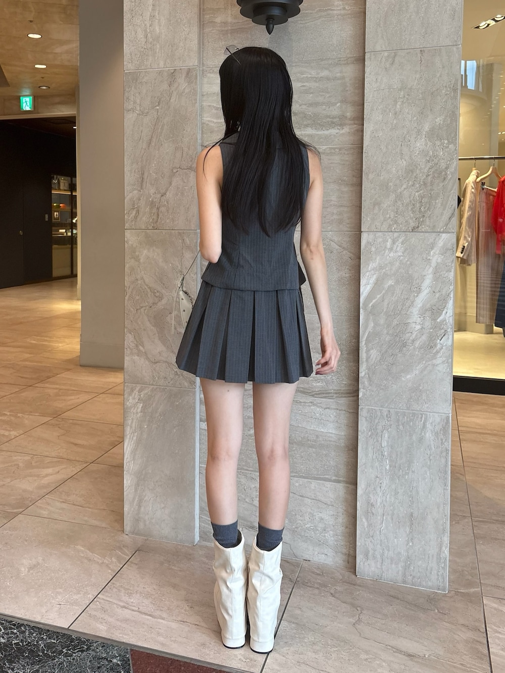 グレー系のワンピース、ホワイト系のサンダル、ホワイト系のハンドバッグを着用したレディースの春コーディネートの3枚目の写真