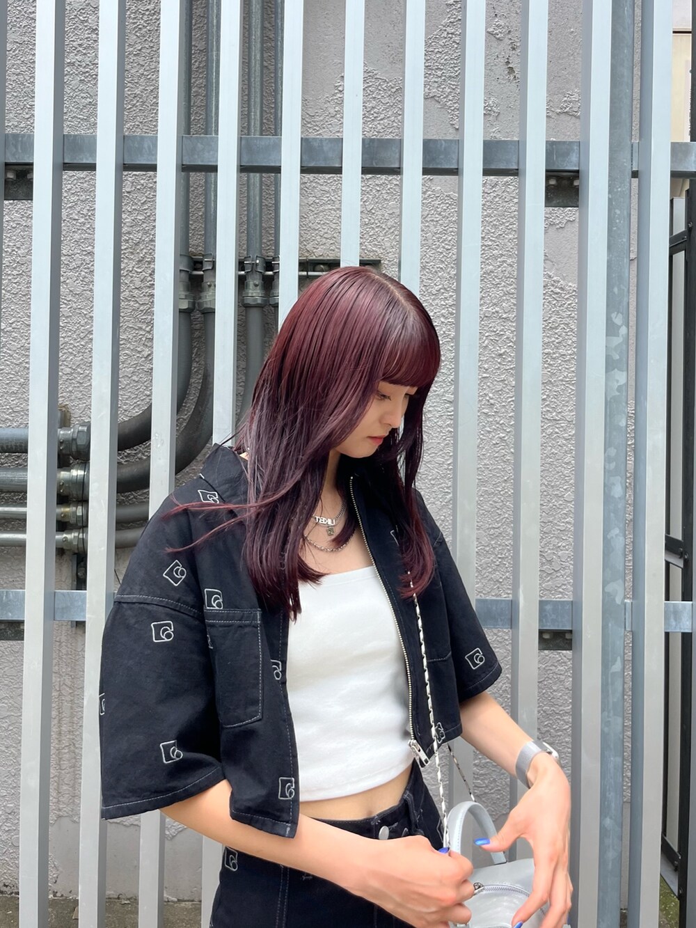 シルバー系のハンドバッグ、ブラック系のデニムスカート、ホワイト系のキャミソールを着用したレディースの夏コーディネートの4枚目の写真