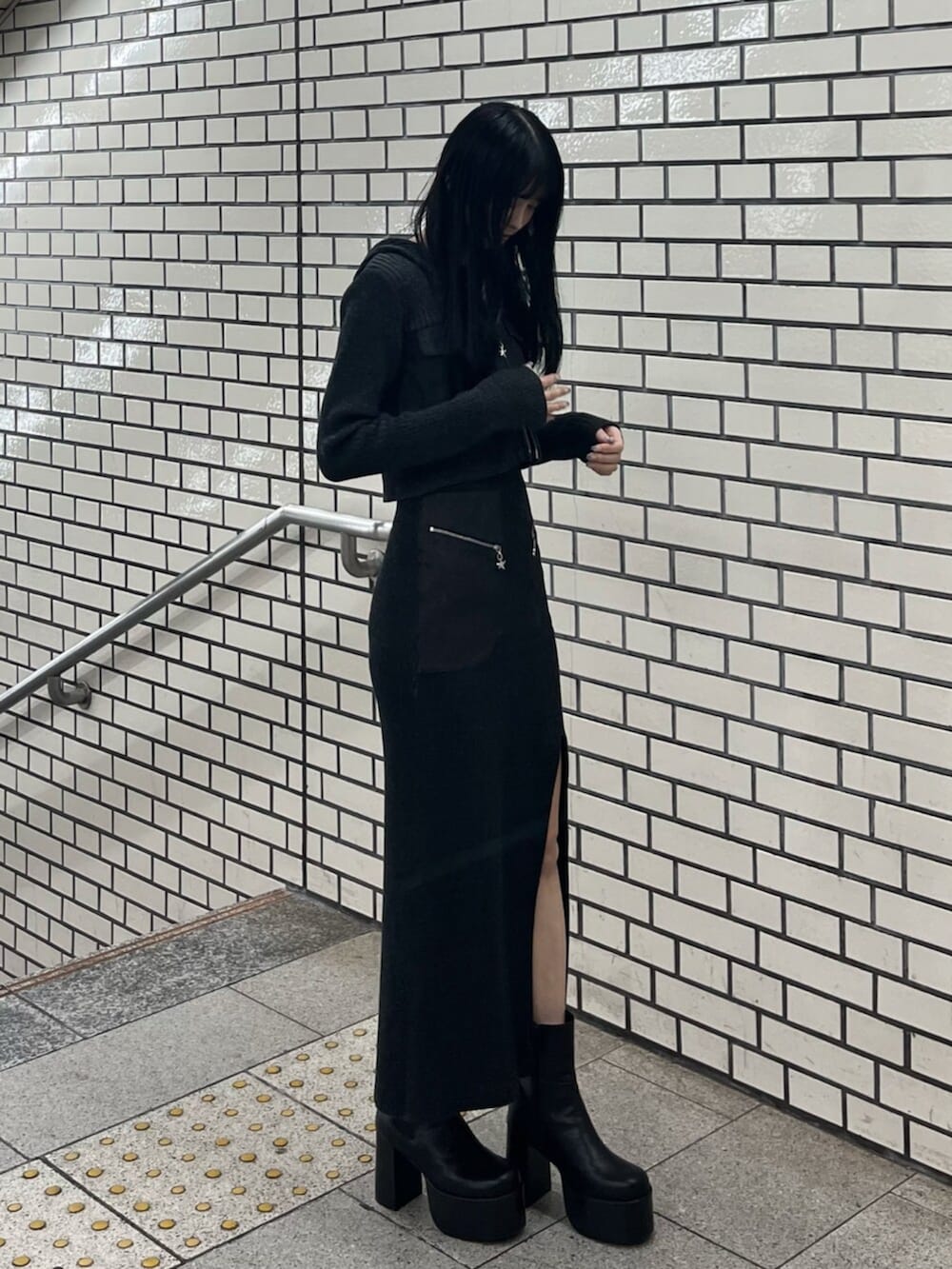 ブラック系のブーツ、ブラック系のニット/セーター、ブラック系のワンピースを着用したレディースの春コーディネートの2枚目の写真