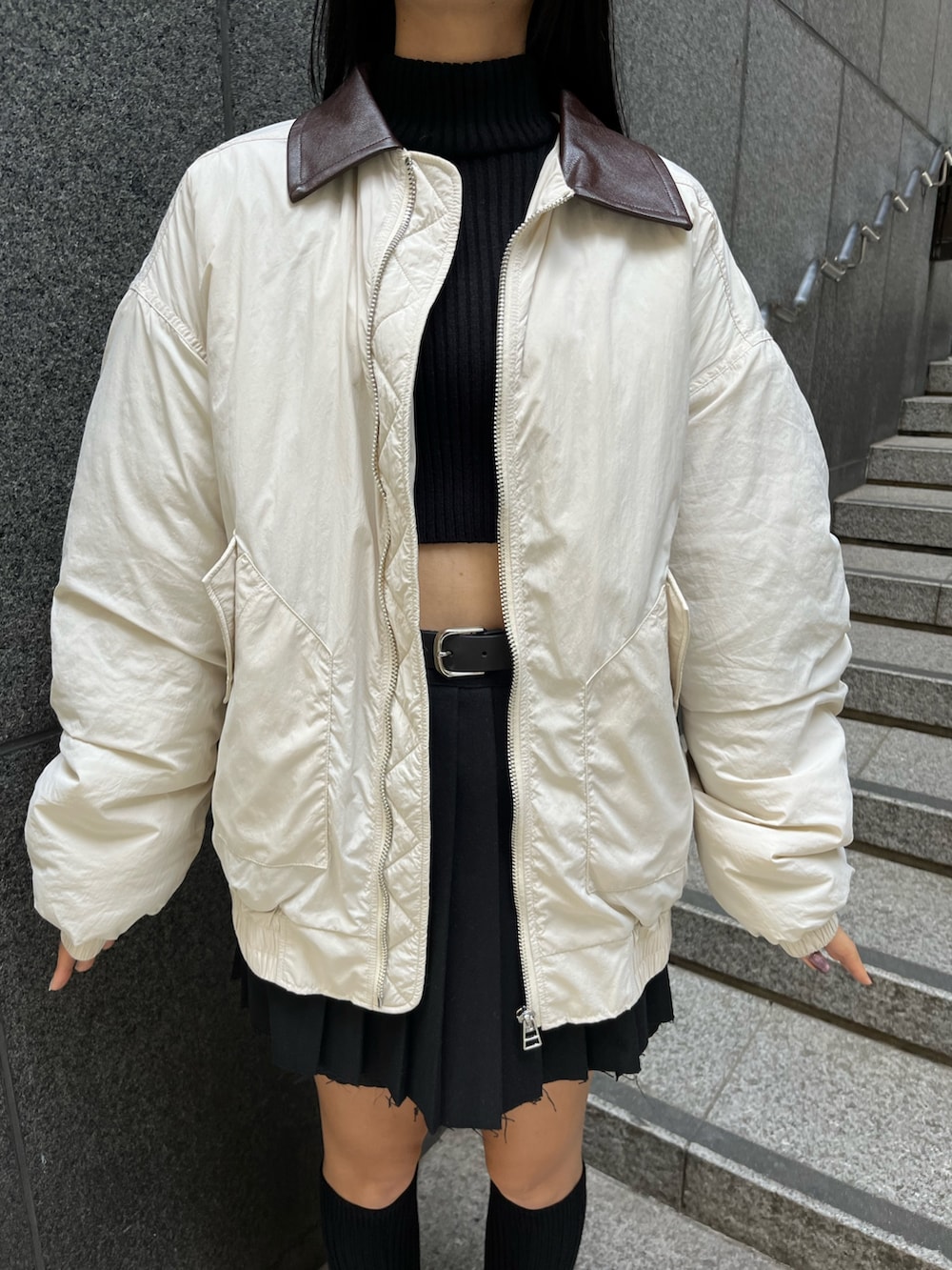 ブラック系のニット/セーター、ブラック系のスカート、ホワイト系のブルゾンを着用したレディースの秋コーディネートの5枚目の写真