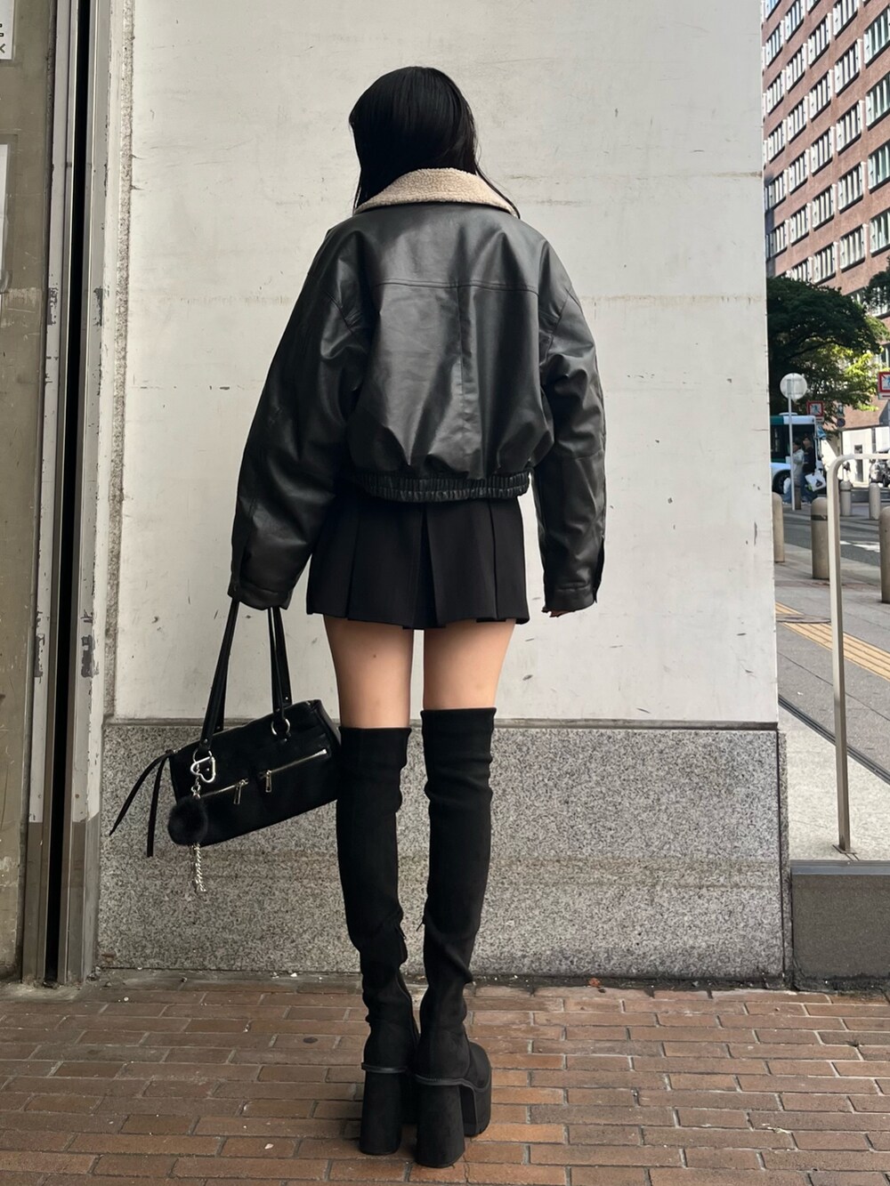 グレー系のブルゾン、ホワイト系のニット/セーター、ブラック系のスカートを着用したレディースの秋コーディネートの3枚目の写真