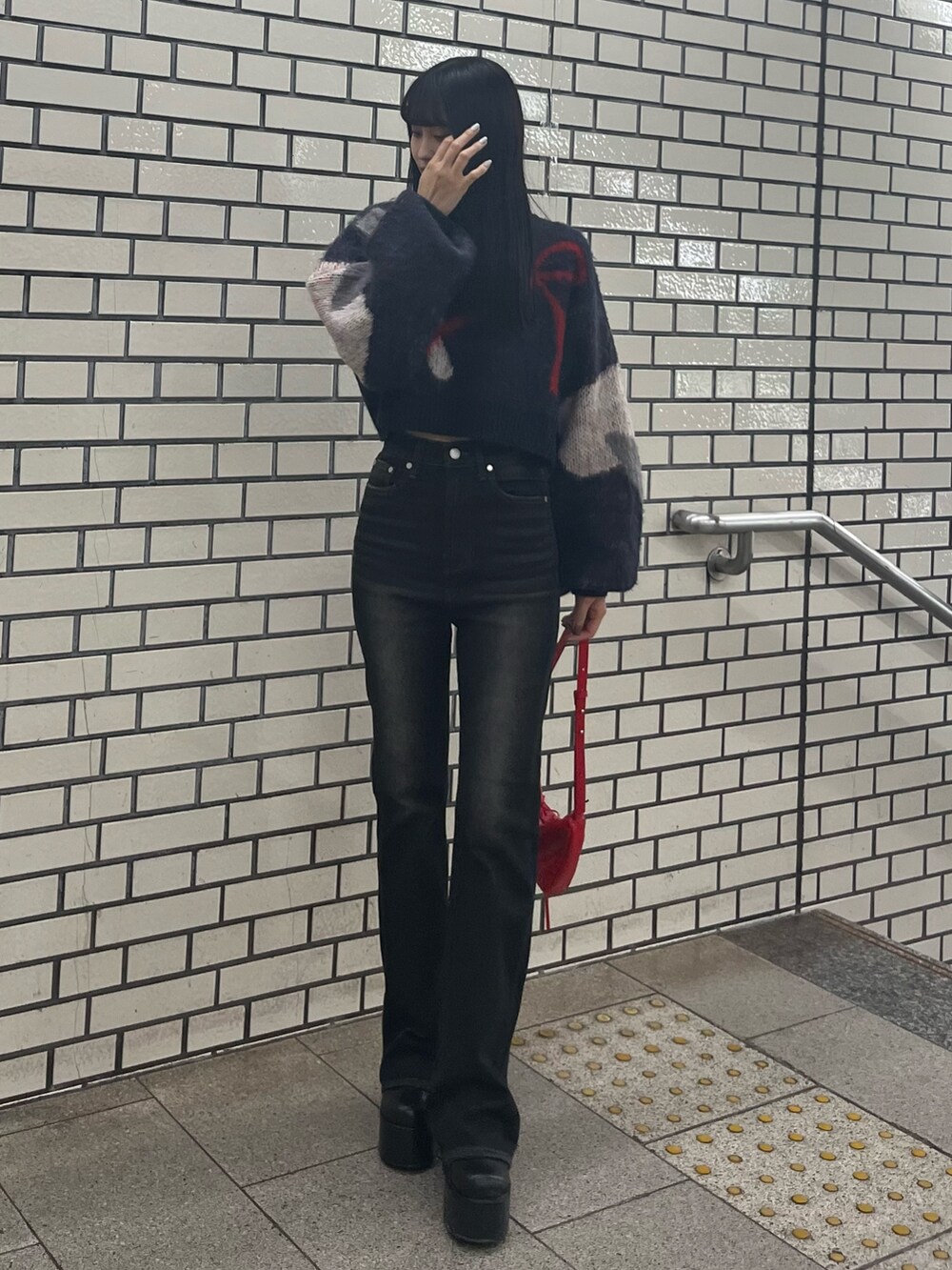 ブラック系のデニムパンツ、ブルー系のニット/セーター、レッド系のショルダーバッグを着用したレディースの秋コーディネートの3枚目の写真