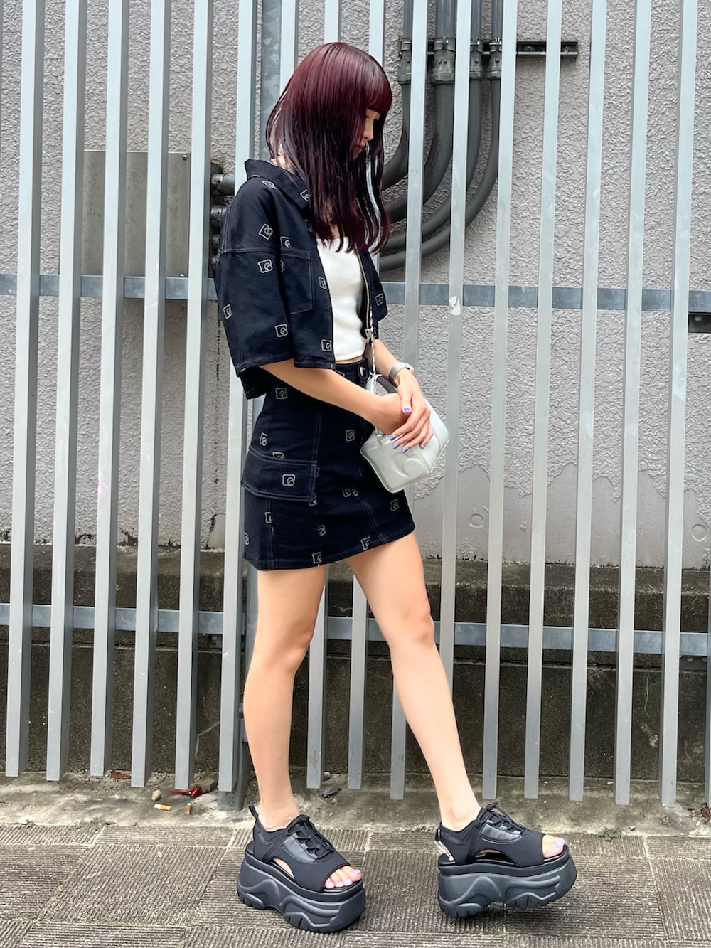 シルバー系のハンドバッグ、ブラック系のデニムスカート、ホワイト系のキャミソールを着用したレディースの夏コーディネートの2枚目の写真