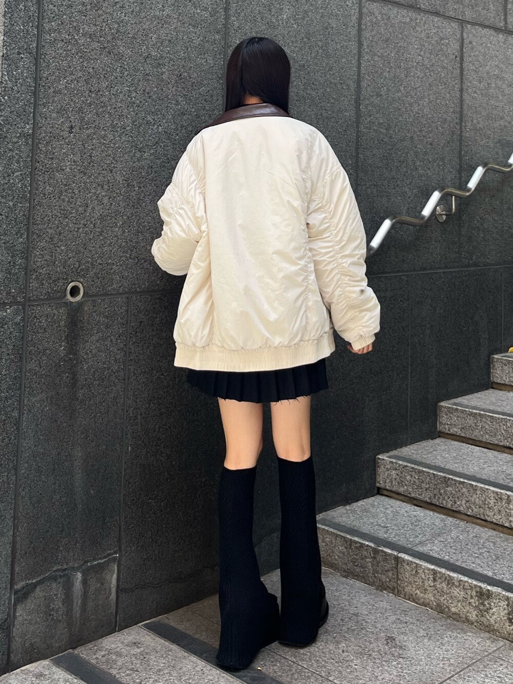 ブラック系のニット/セーター、ブラック系のスカート、ホワイト系のブルゾンを着用したレディースの秋コーディネートの3枚目の写真