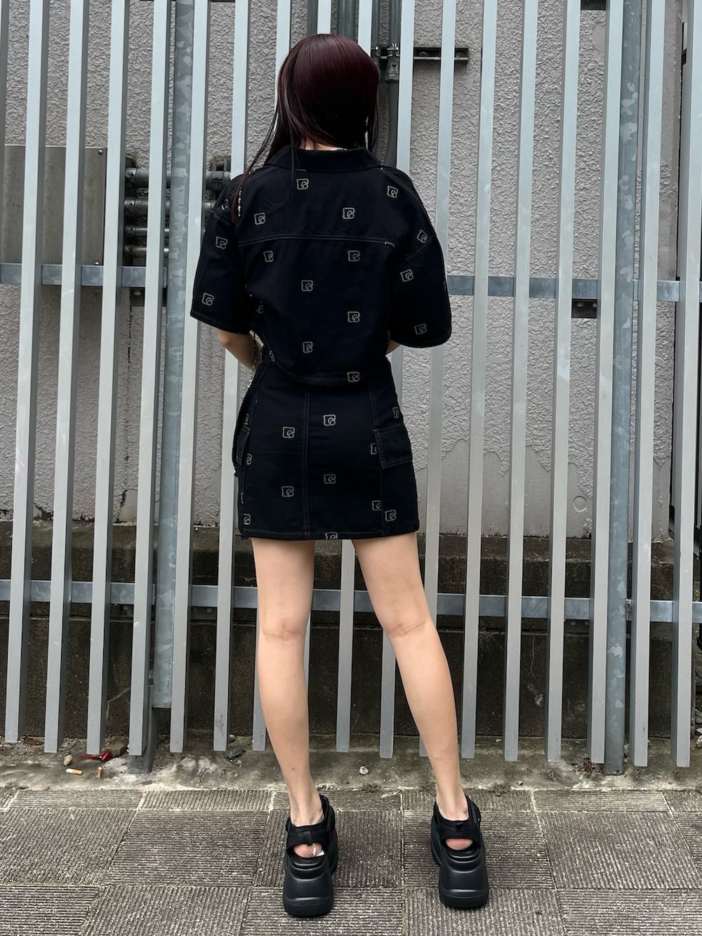 シルバー系のハンドバッグ、ブラック系のデニムスカート、ホワイト系のキャミソールを着用したレディースの夏コーディネートの3枚目の写真