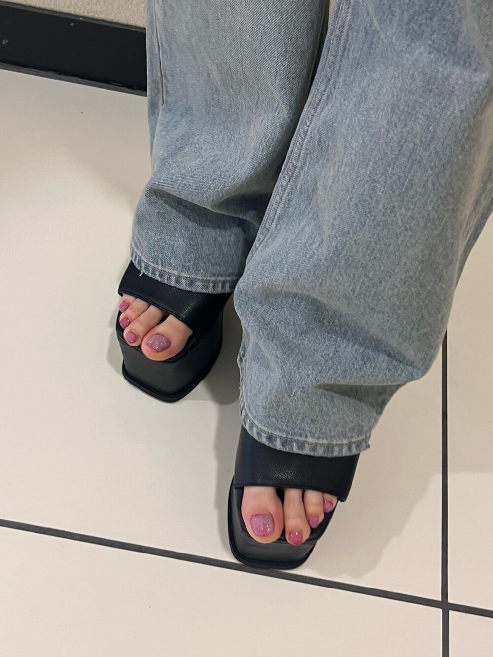 ブラック系のニット/セーター、ブルー系のデニムパンツ、ブラック系のサンダルを着用したレディースの春コーディネートの7枚目の写真