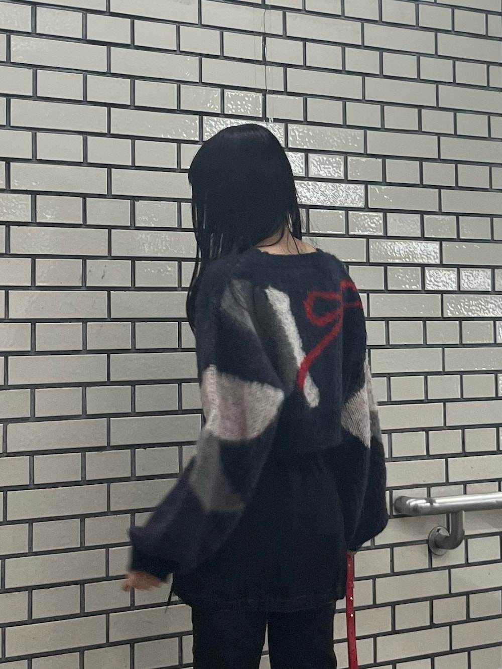 ブラック系のデニムパンツ、ブルー系のニット/セーター、レッド系のショルダーバッグを着用したレディースの秋コーディネートの5枚目の写真