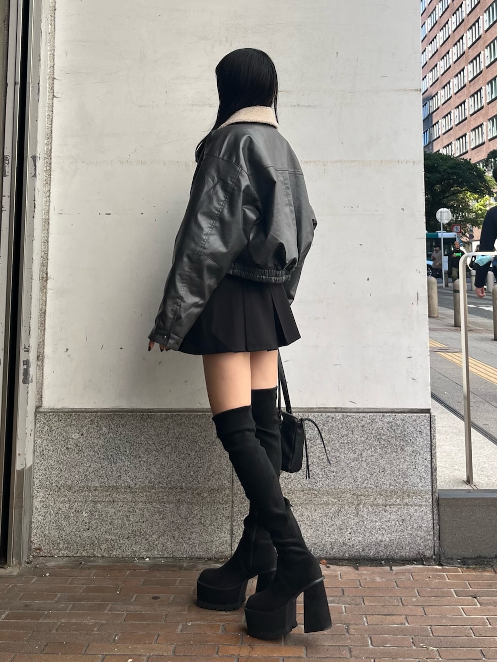 グレー系のブルゾン、ホワイト系のニット/セーター、ブラック系のスカートを着用したレディースの秋コーディネートの2枚目の写真