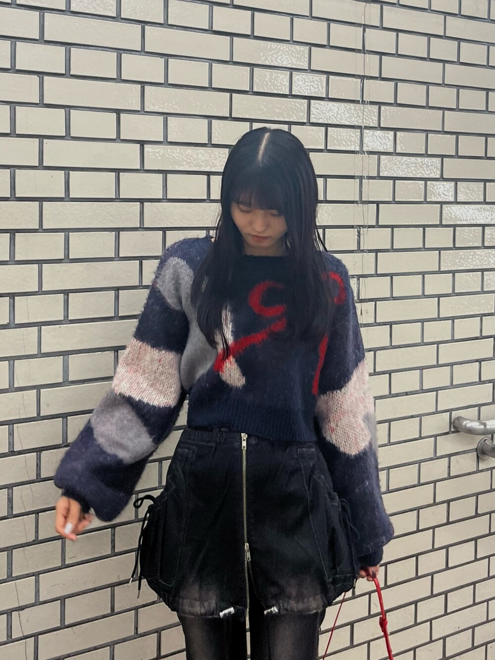 ブラック系のデニムパンツ、ブルー系のニット/セーター、レッド系のショルダーバッグを着用したレディースの秋コーディネートの4枚目の写真