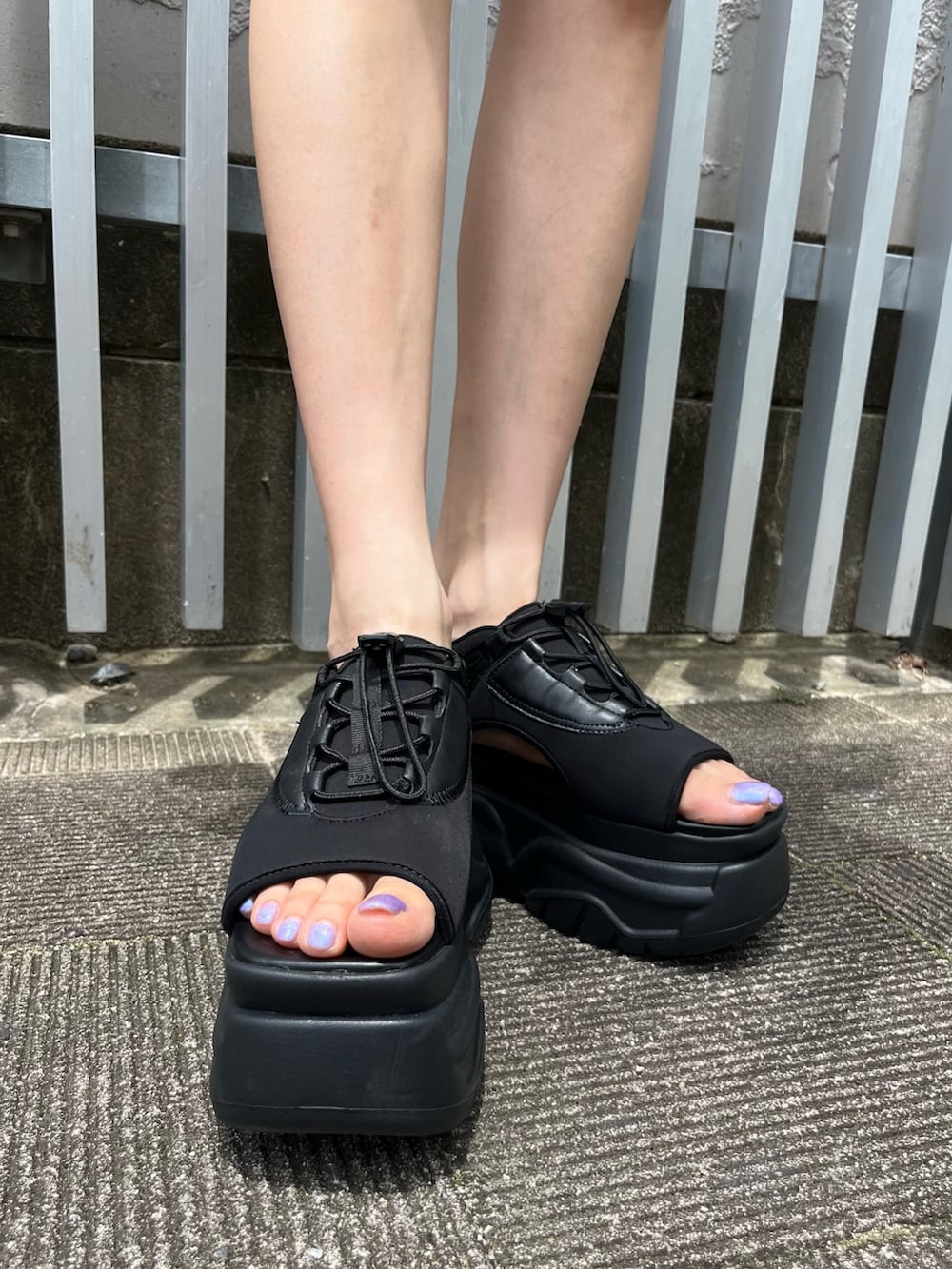 シルバー系のハンドバッグ、ブラック系のデニムスカート、ホワイト系のキャミソールを着用したレディースの夏コーディネートの7枚目の写真