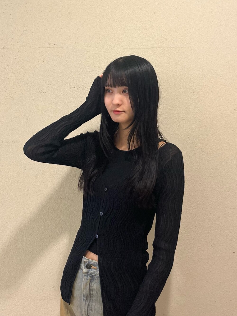 ブラック系のニット/セーター、ブルー系のデニムパンツ、ブラック系のサンダルを着用したレディースの春コーディネートの4枚目の写真