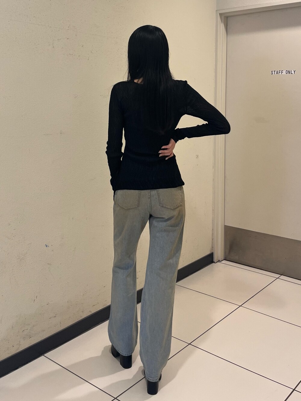 ブラック系のニット/セーター、ブルー系のデニムパンツ、ブラック系のサンダルを着用したレディースの春コーディネートの3枚目の写真