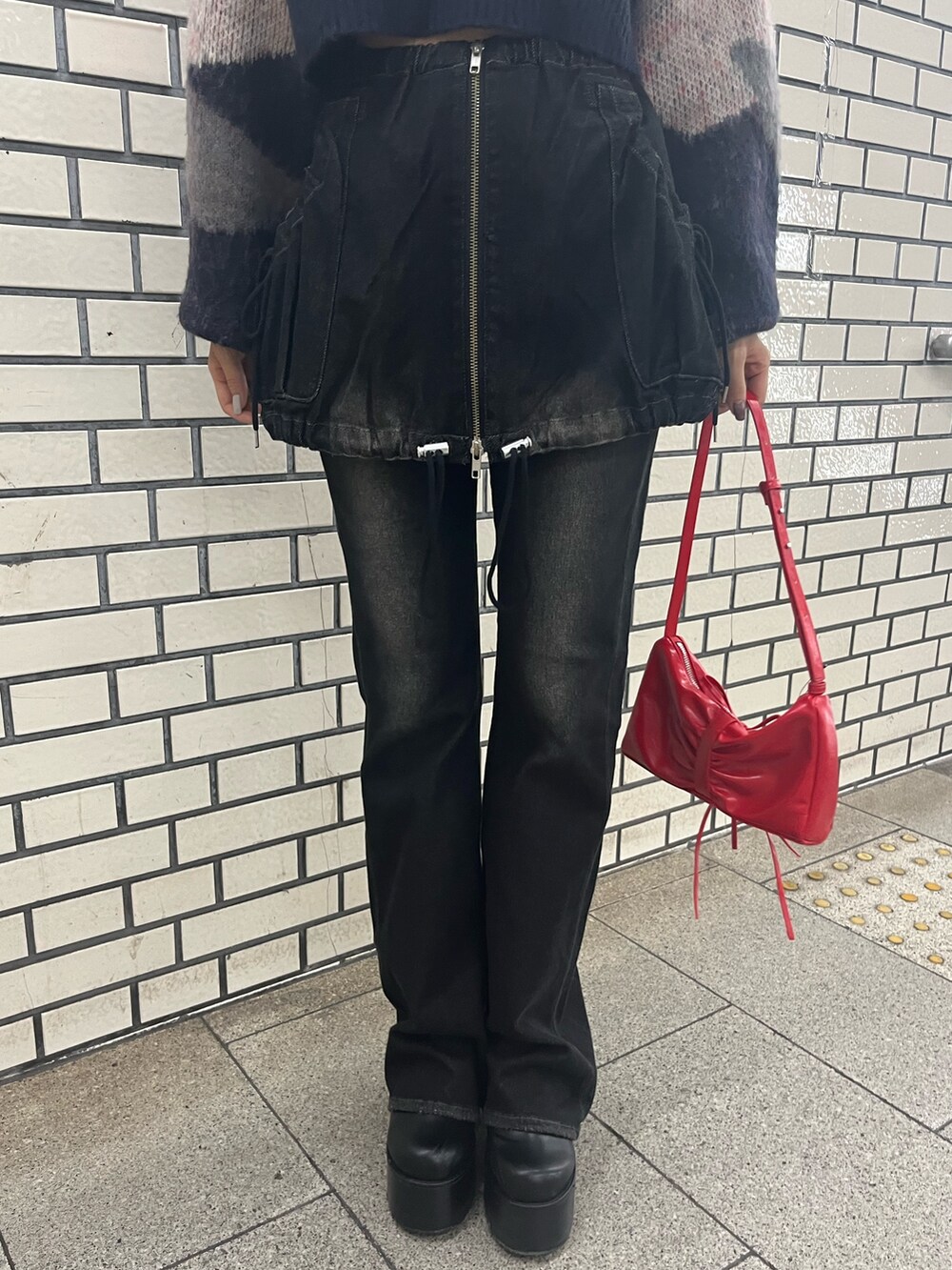 ブラック系のデニムパンツ、ブルー系のニット/セーター、レッド系のショルダーバッグを着用したレディースの秋コーディネートの7枚目の写真