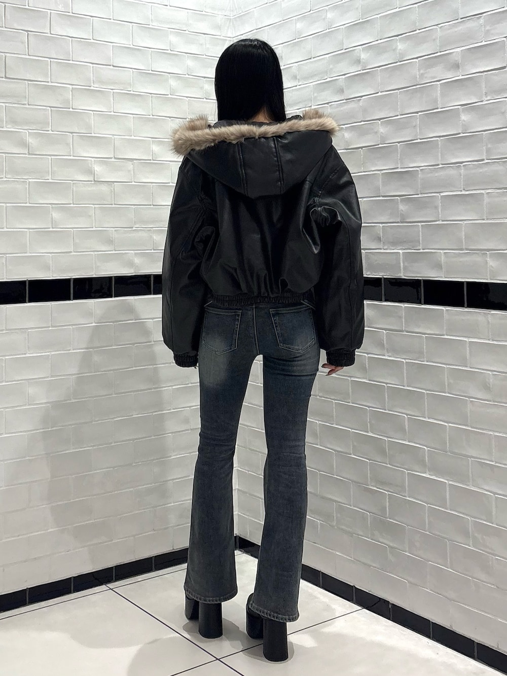 ブラック系のTシャツ/カットソー、ブラック系のブルゾン、ブルー系のデニムパンツを着用したレディースの秋コーディネートの3枚目の写真