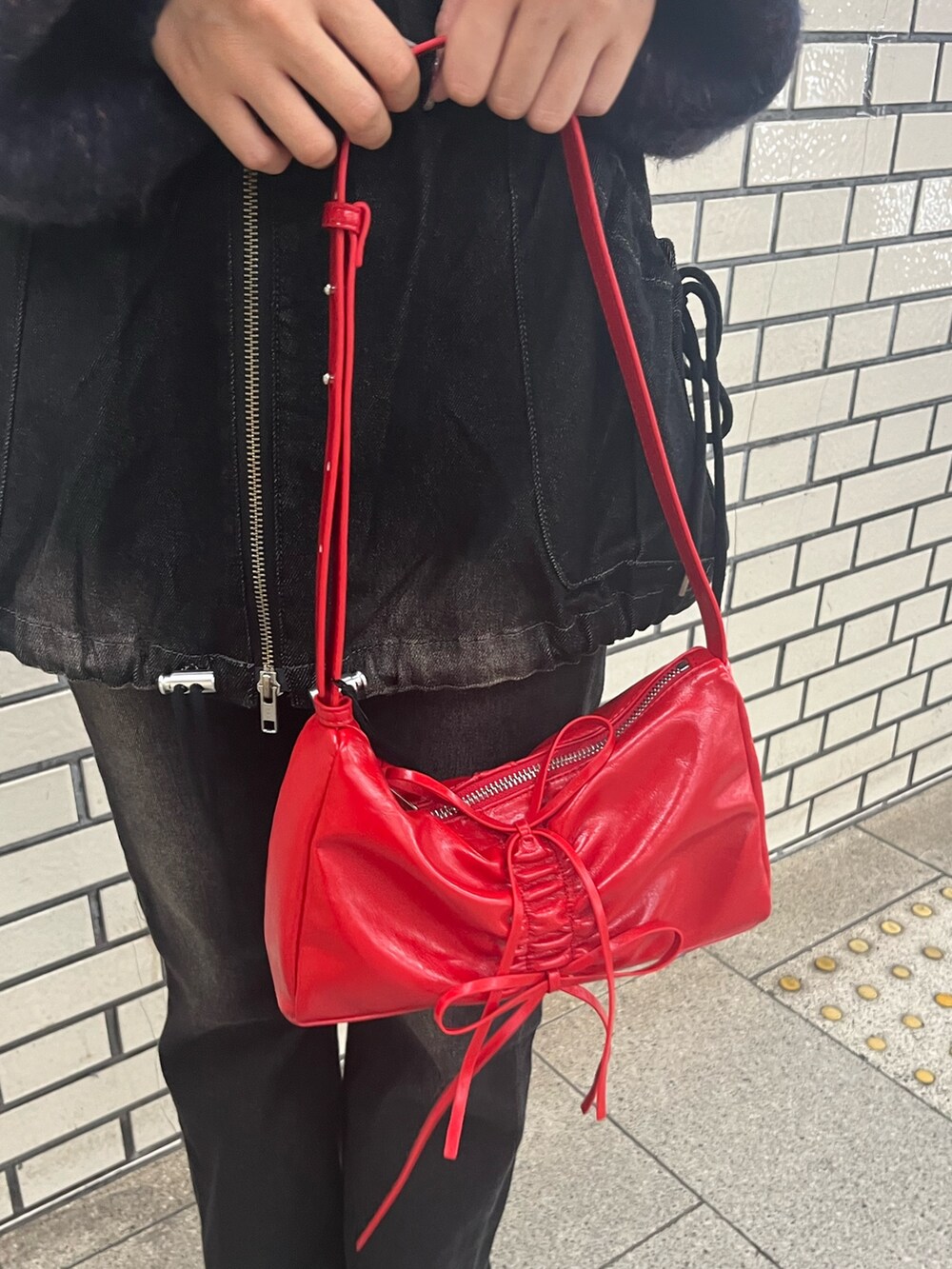 ブラック系のデニムパンツ、ブルー系のニット/セーター、レッド系のショルダーバッグを着用したレディースの秋コーディネートの9枚目の写真