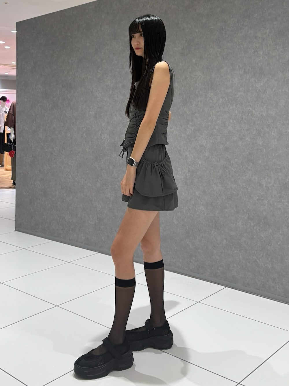 グレー系のTシャツ/カットソー、グレー系のスカート、ブラック系のスニーカーを着用したレディースの夏コーディネートの2枚目の写真