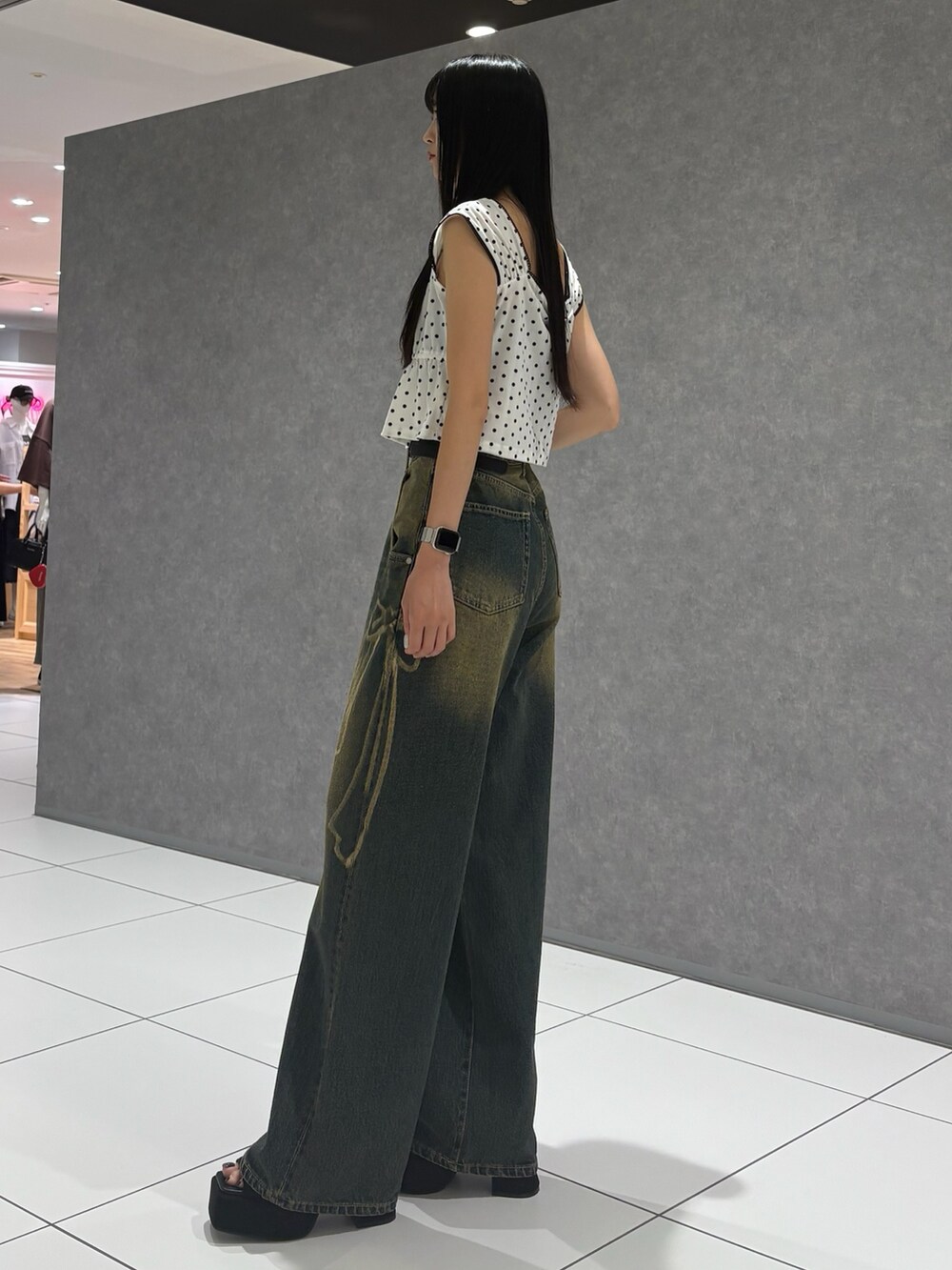 ホワイト系のタンクトップ、ブルー系のデニムパンツ、ブラック系のサンダルを着用したレディースの夏コーディネートの2枚目の写真