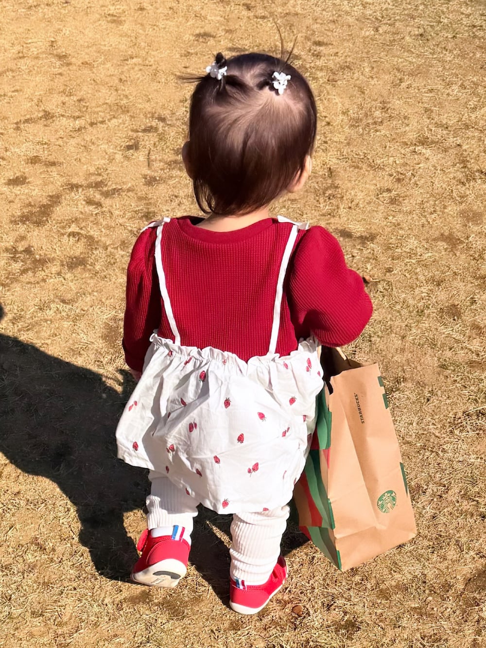 レッド系のTシャツ/カットソー、レッド系のスニーカー、ホワイト系のパンツを着用したキッズの秋コーディネートの2枚目の写真