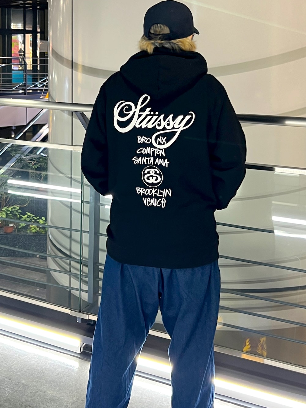 ブラック系のパーカー、ブルー系のデニムパンツ、ブラック系のキャップを着用したメンズの春コーディネートの2枚目の写真