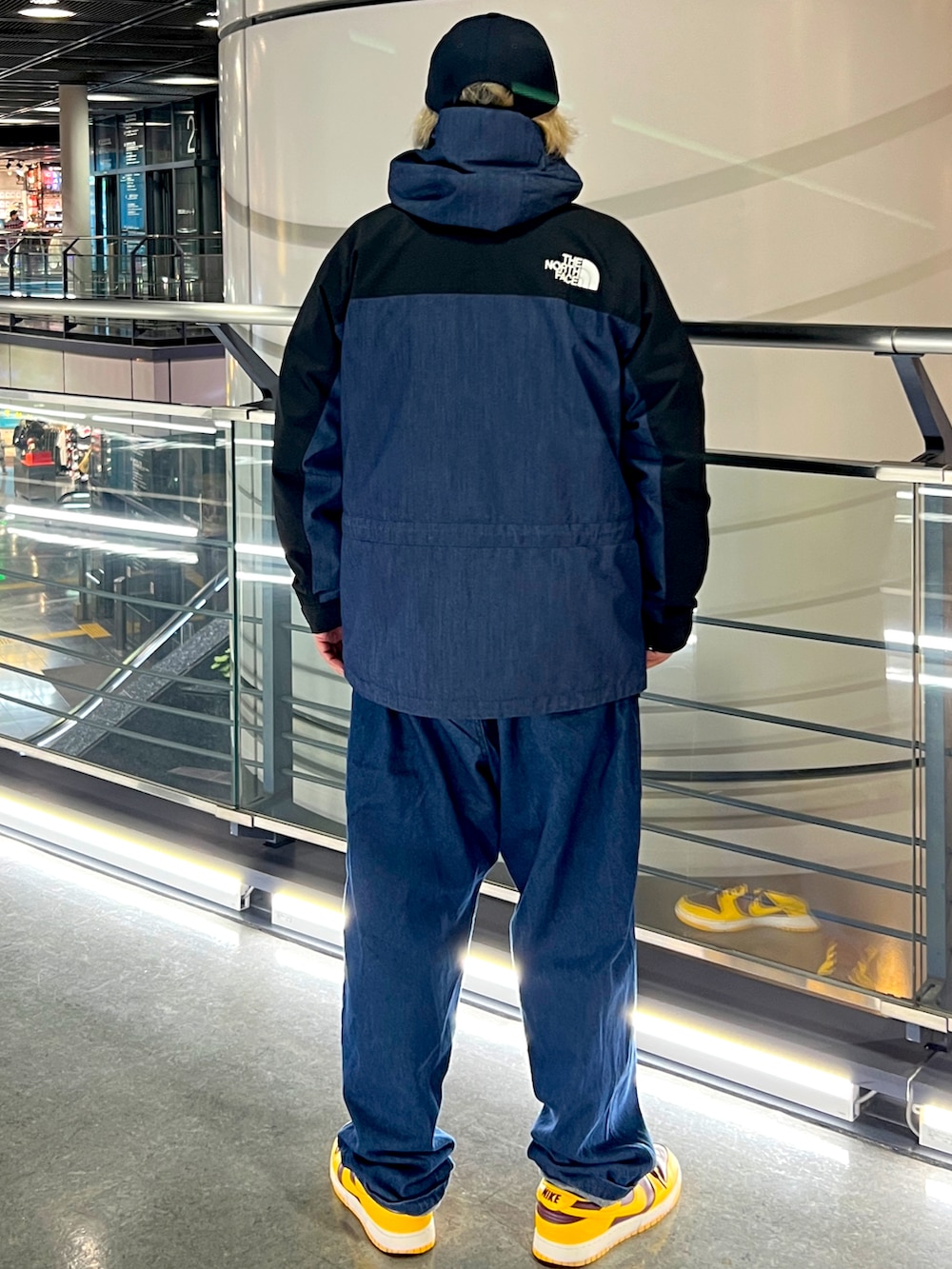 ブルー系のチノパンツ、イエロー系のスニーカー、ブルー系のマウンテンパーカーを着用したメンズの冬コーディネートの2枚目の写真