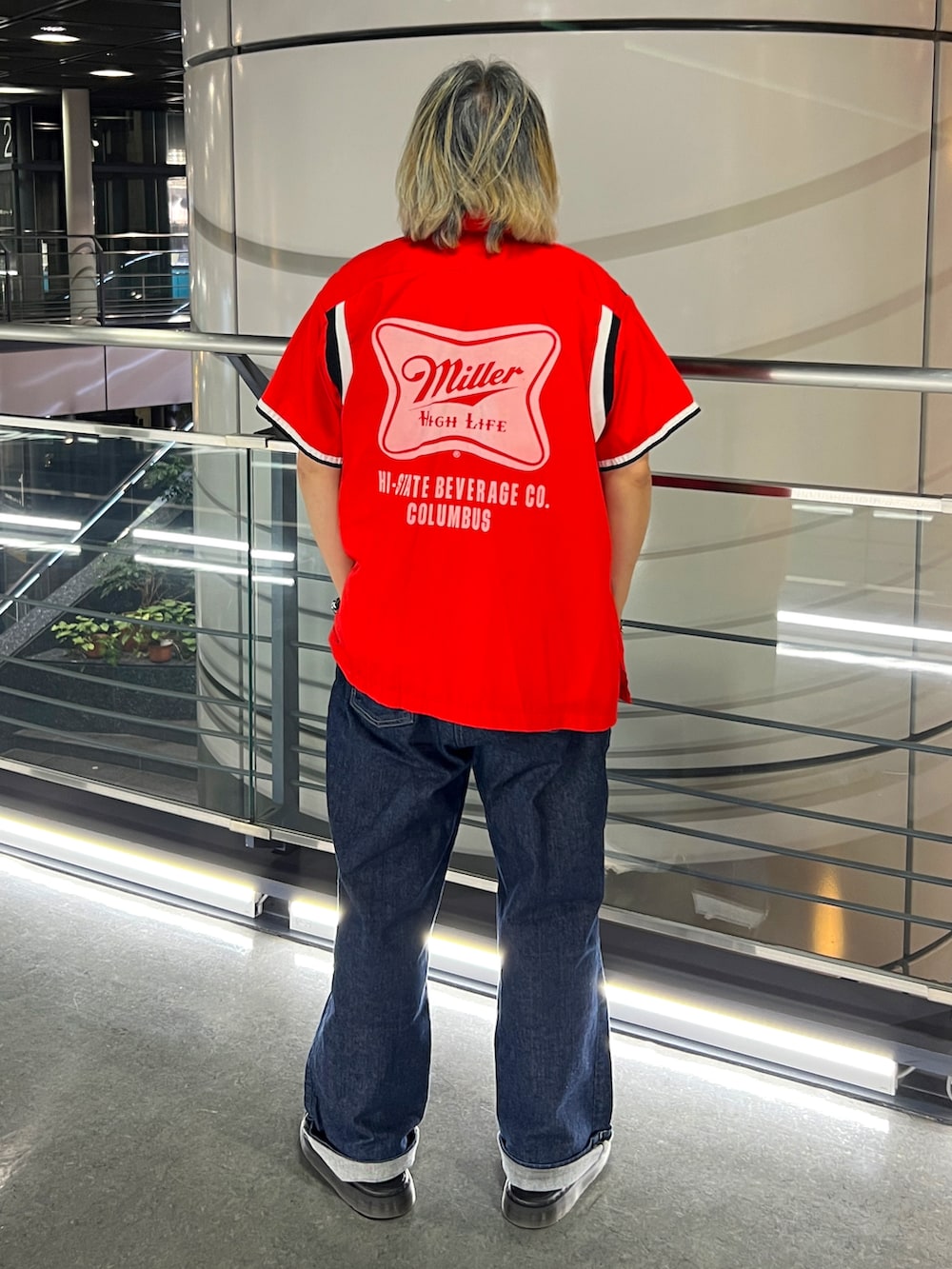 レッド系のシャツ/ブラウス、ブルー系のデニムパンツ、ブラック系のスリッポンを着用したメンズの春コーディネートの2枚目の写真