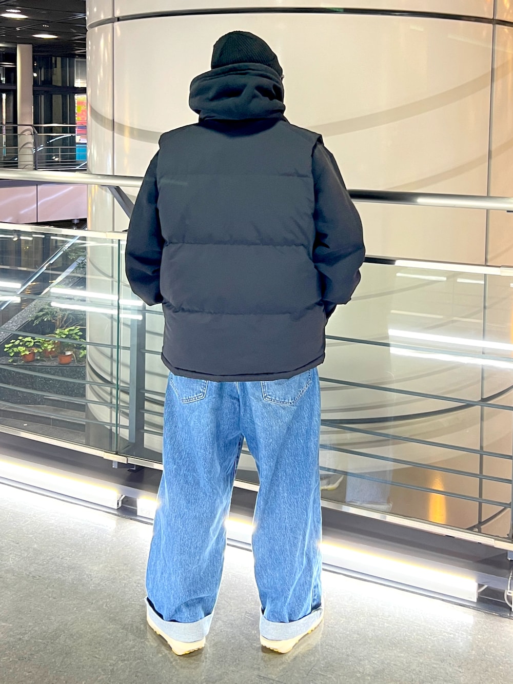 ブラック系のパーカー、ブルー系のデニムパンツ、ブラック系のダウンベストを着用したメンズの冬コーディネートの2枚目の写真