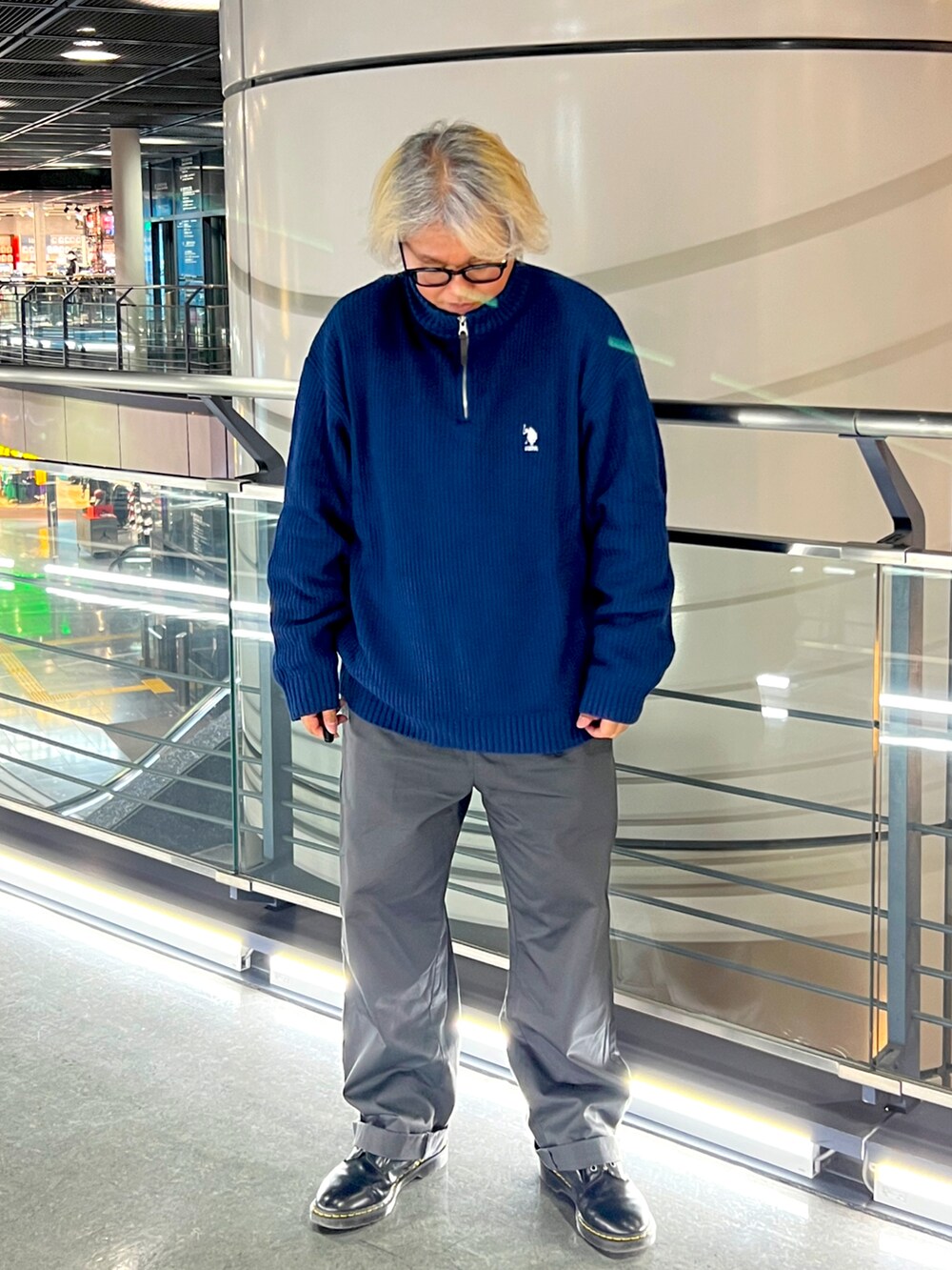 ブラック系のライダースジャケット、ブルー系のニット/セーター、グレー系のチノパンツを着用したメンズの春コーディネートの3枚目の写真