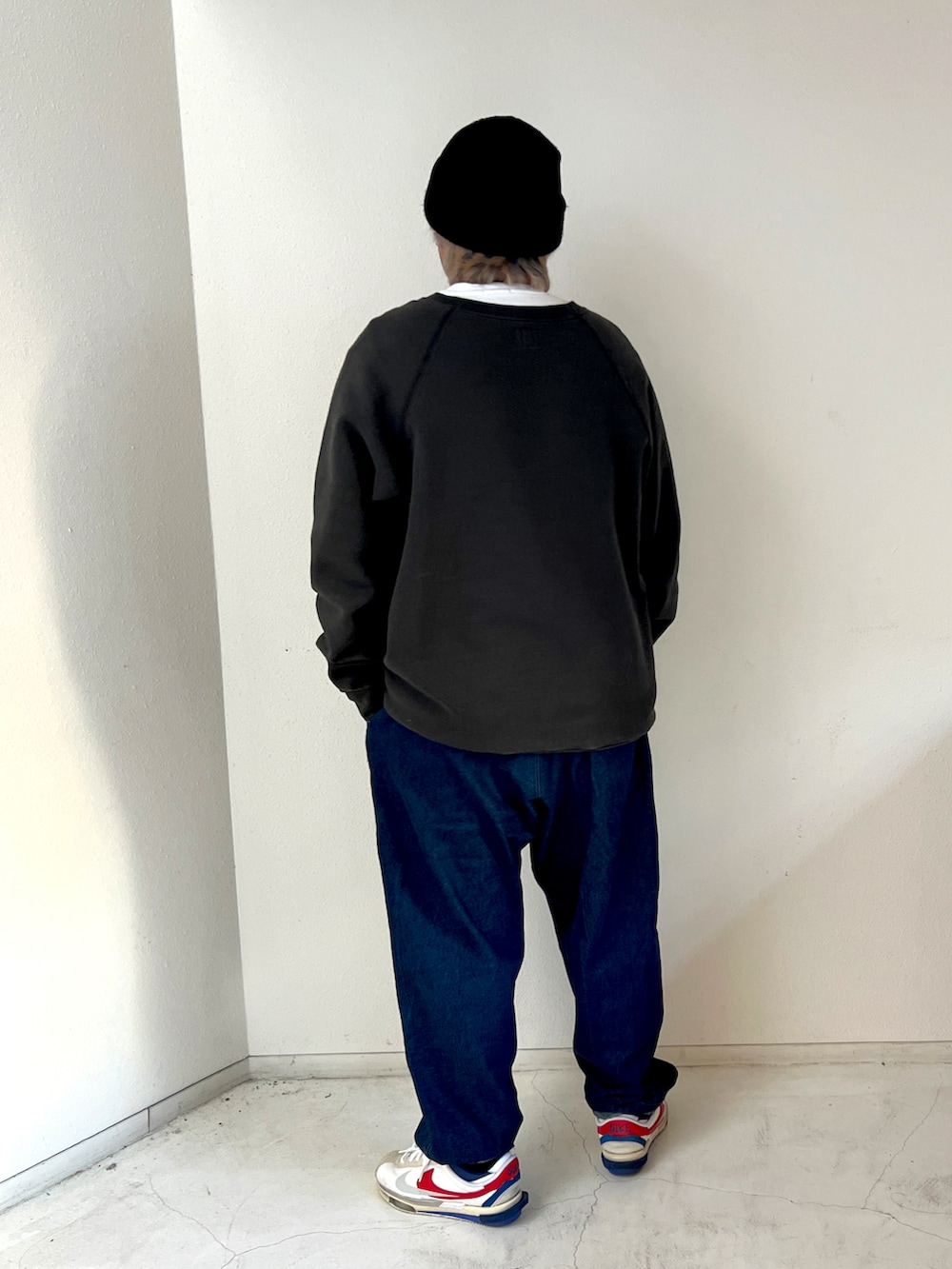 グレー系のスウェット、ブルー系のデニムパンツ、ホワイト系のスニーカーを着用したメンズの冬コーディネートの2枚目の写真