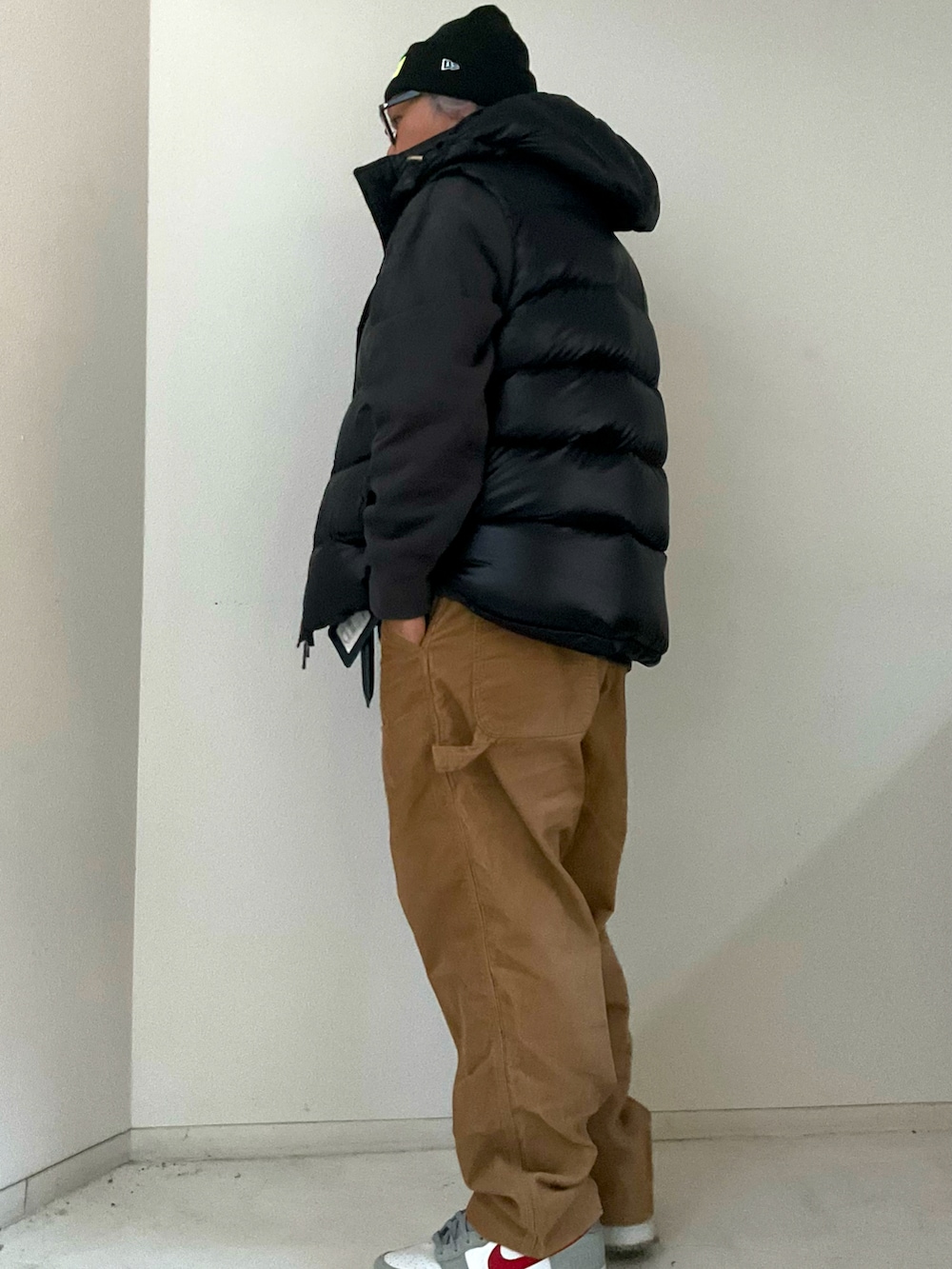 ブラック系のダウンベスト、グレー系のスニーカー、ブラック系のニットキャップ/ビーニーを着用したメンズの冬コーディネートの2枚目の写真