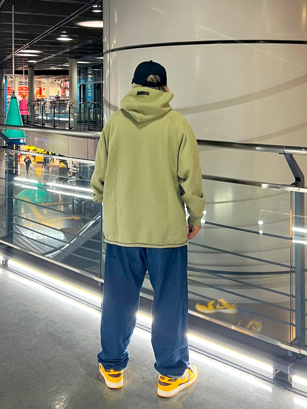 グリーン系のニット/セーター、ブルー系のデニムパンツ、ブラック系のキャップを着用したメンズの冬コーディネートの2枚目の写真