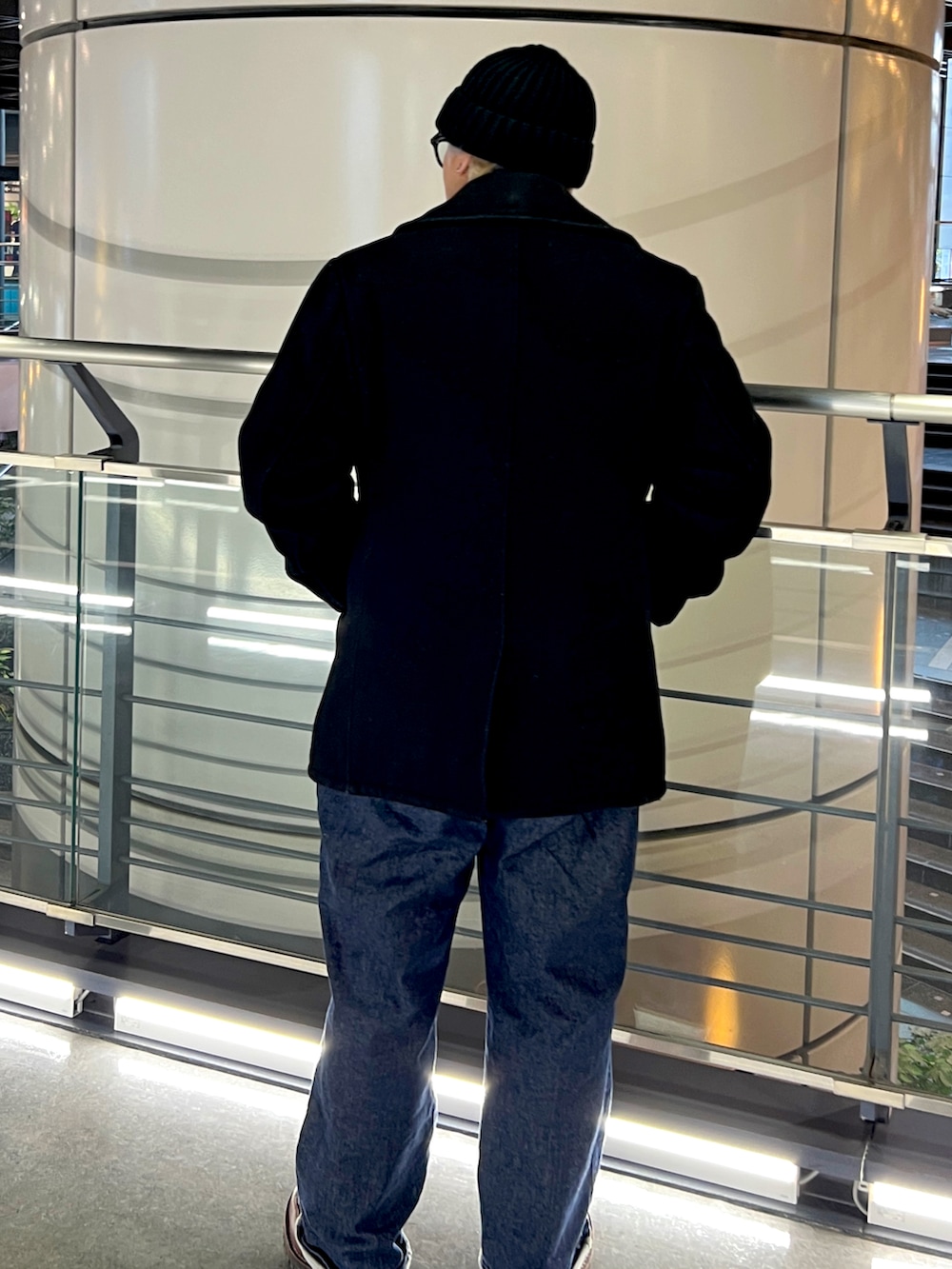 ブラウン系のブーツ、ブルー系のデニムパンツ、ブラック系のピーコートを着用したメンズの冬コーディネートの2枚目の写真