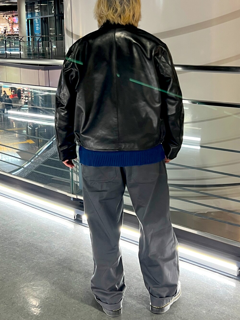 ブラック系のライダースジャケット、ブルー系のニット/セーター、グレー系のチノパンツを着用したメンズの春コーディネートの2枚目の写真