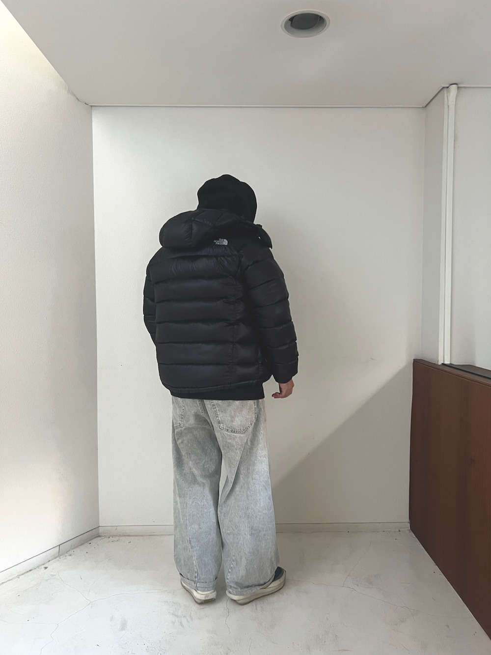 グレー系のデニムパンツ、ブラック系のダウンジャケット/コート、ブラック系のパーカーを着用したメンズの冬コーディネートの2枚目の写真