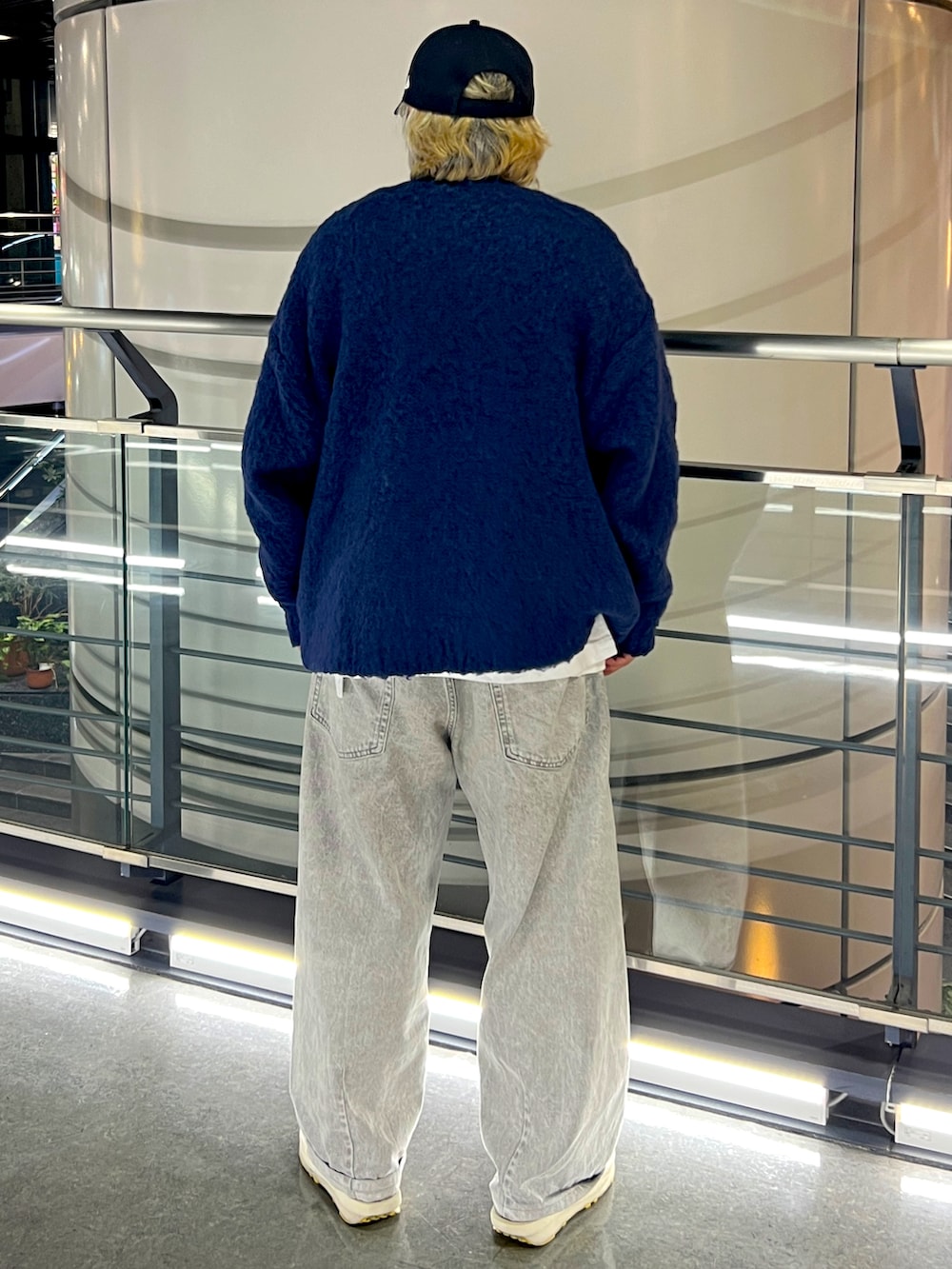 ブルー系のニット/セーター、グレー系のデニムパンツ、ブラック系のキャップを着用したメンズの春コーディネートの2枚目の写真