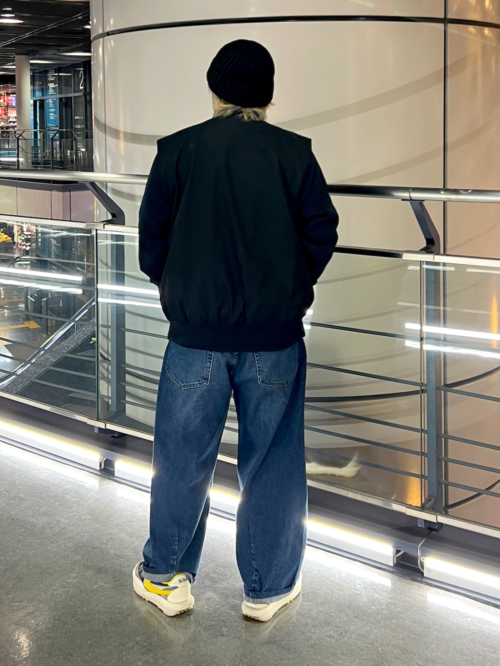 ブラック系のベスト、ブルー系のデニムパンツ、ブラック系のスニーカーを着用したメンズの冬コーディネートの2枚目の写真