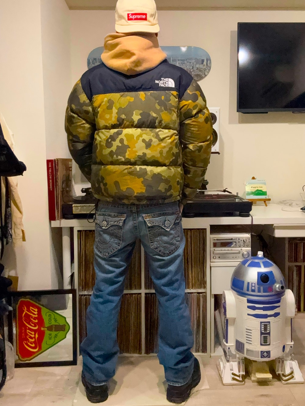 グリーン系のダウンジャケット/コート、ベージュ系のパーカー、ブルー系のデニムパンツを着用したメンズの春コーディネートの2枚目の写真