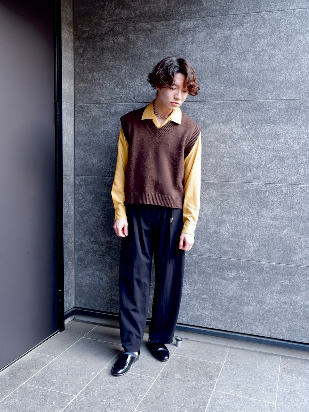 ブラック系のスリッポン、ブラウン系のベスト、イエロー系のシャツ/ブラウスを着用したメンズの春コーディネートの2枚目の写真