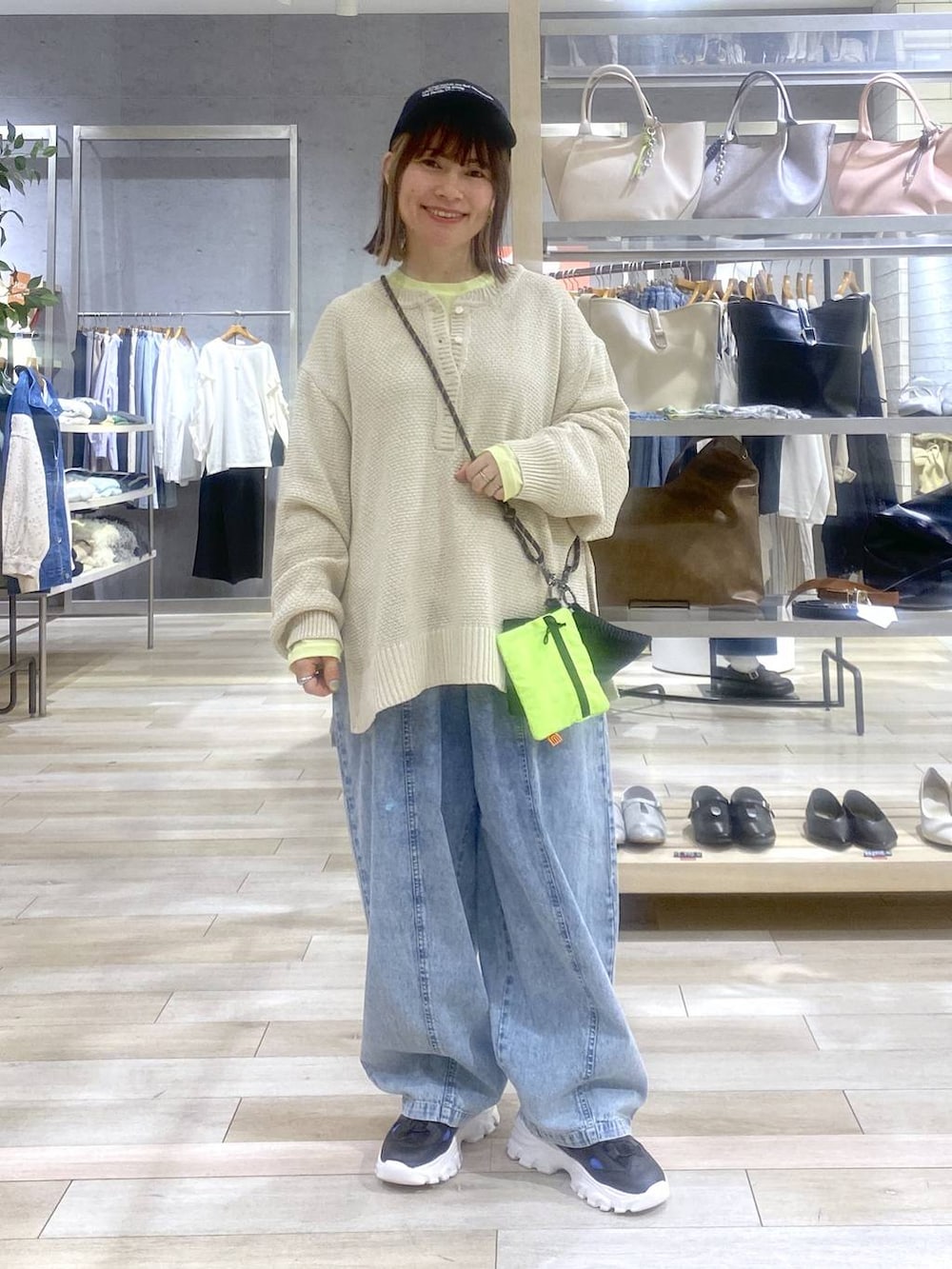 イエロー系のTシャツ/カットソー、ベージュ系のニット/セーター、ブラック系のサンダルを着用したレディースの春コーディネートの2枚目の写真