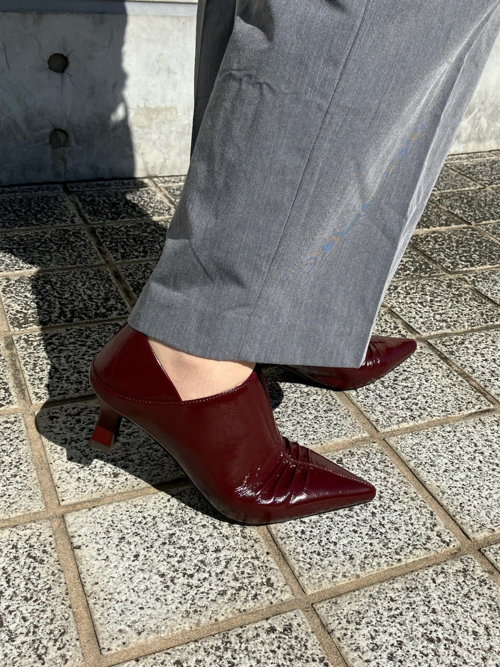 レッド系のパンプス、レッド系のショルダーバッグを着用したレディースの秋コーディネートの2枚目の写真