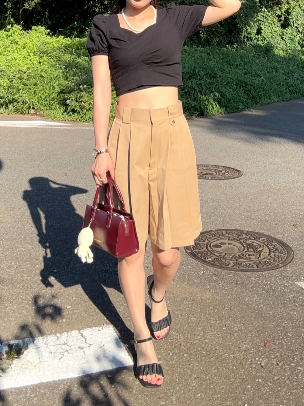 ブラック系のトップス、その他のハンドバッグ、ベージュ系のその他パンツを着用したレディースの夏コーディネートの3枚目の写真