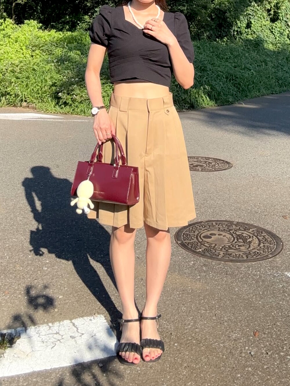 ブラック系のトップス、その他のハンドバッグ、ベージュ系のその他パンツを着用したレディースの夏コーディネートの4枚目の写真
