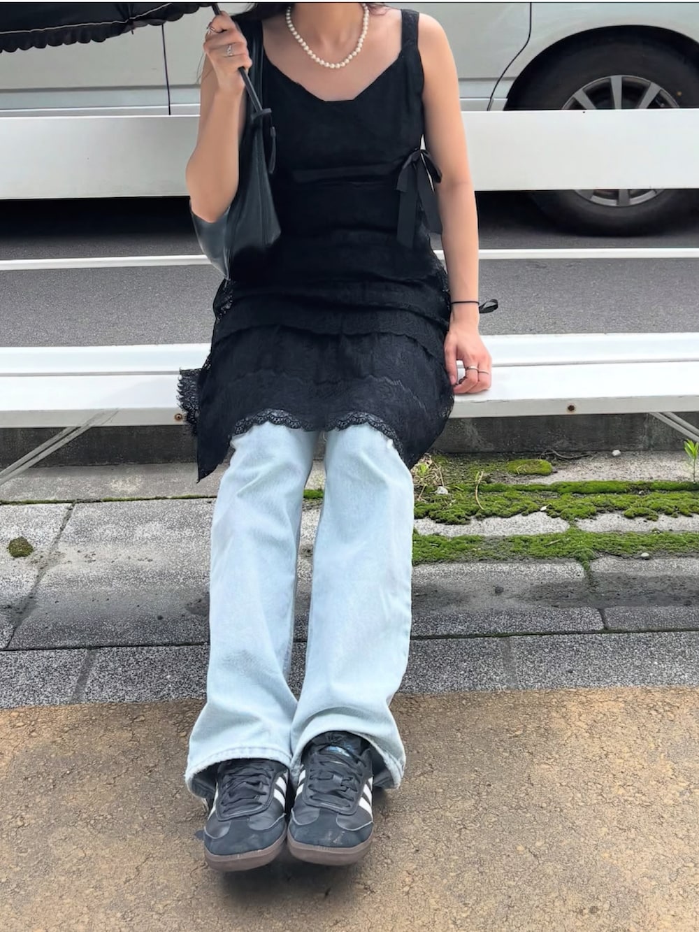 ブラック系のハンドバッグ、ブルー系のデニムパンツ、ブラック系のスニーカーを着用したレディースの夏コーディネートの2枚目の写真