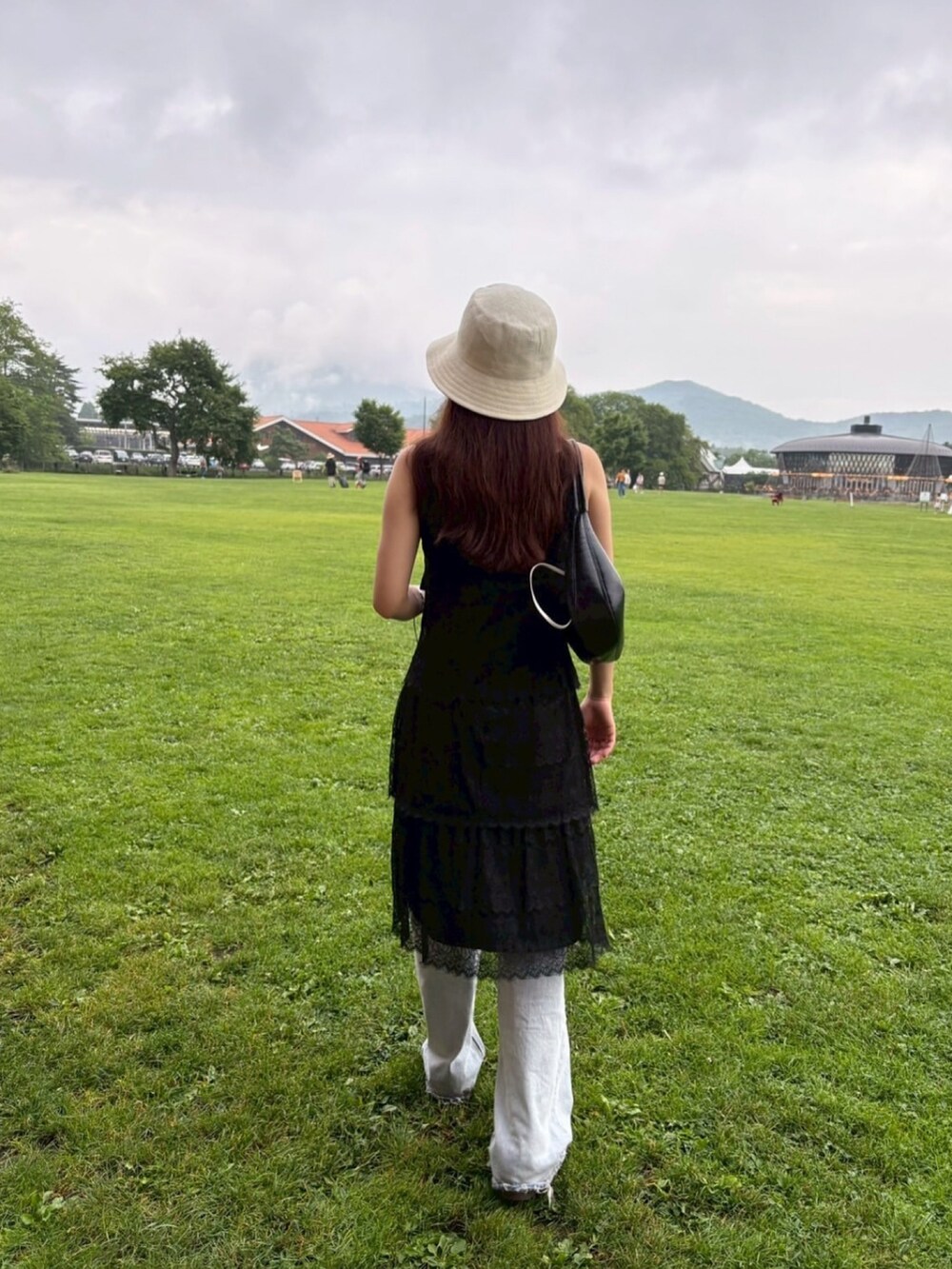 ブラック系のハンドバッグ、ブルー系のデニムパンツ、ブラック系のスニーカーを着用したレディースの夏コーディネートの3枚目の写真