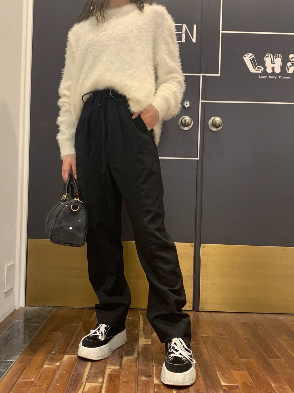 ブラック系のパンツ、ホワイト系のニット/セーター、グレー系のボストンバッグを着用したレディースの冬コーディネートの2枚目の写真