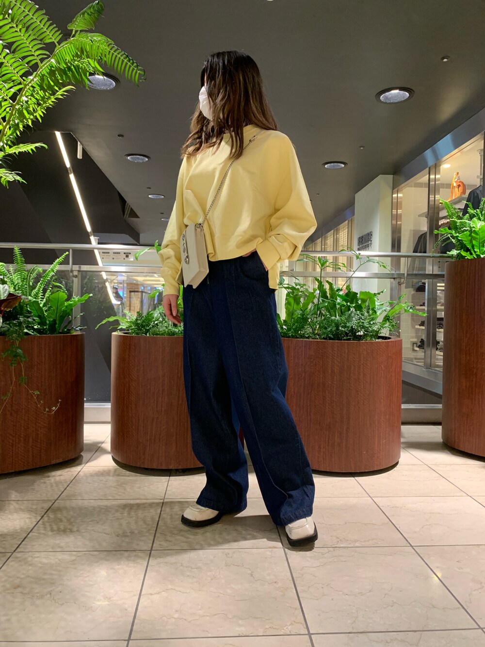 ブルー系のデニムパンツ、イエロー系のスウェット、ホワイト系のショルダーバッグを着用したレディースの冬コーディネートの2枚目の写真
