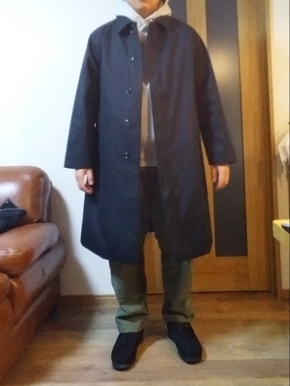 グリーン系のチノパンツ、ブルー系のステンカラーコート、グレー系のパーカーを着用したメンズの冬コーディネートの2枚目の写真