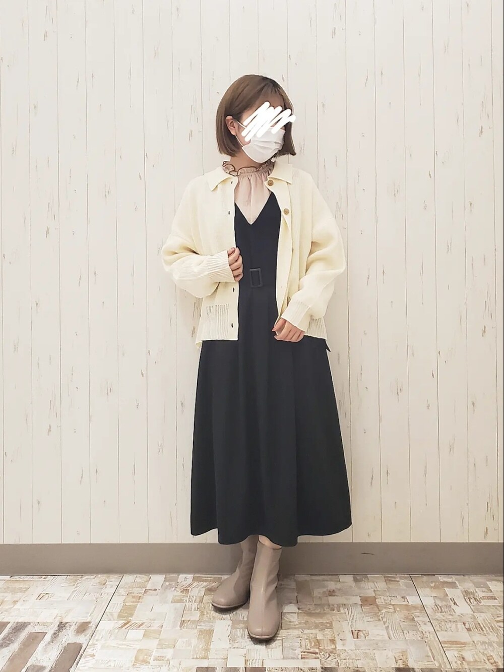 ホワイト系のカーディガン/ボレロ、ブラック系のジャンパースカート、ブラウン系のブーツを着用したレディースの冬コーディネートの2枚目の写真