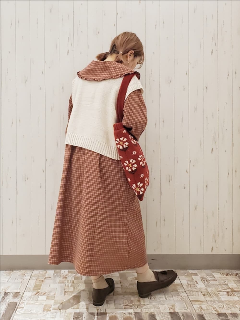 レッド系のワンピース、ホワイト系のベスト、レッド系のハンドバッグを着用したレディースの秋コーディネートの2枚目の写真