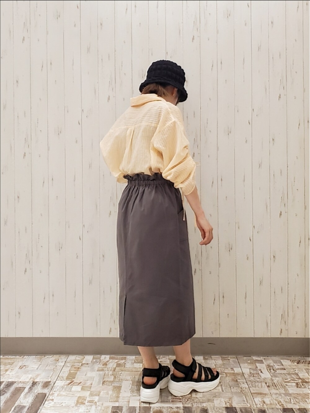 オレンジ系のシャツ/ブラウス、グレー系のスカート、ブラック系のサンダルを着用したレディースの夏コーディネートの2枚目の写真