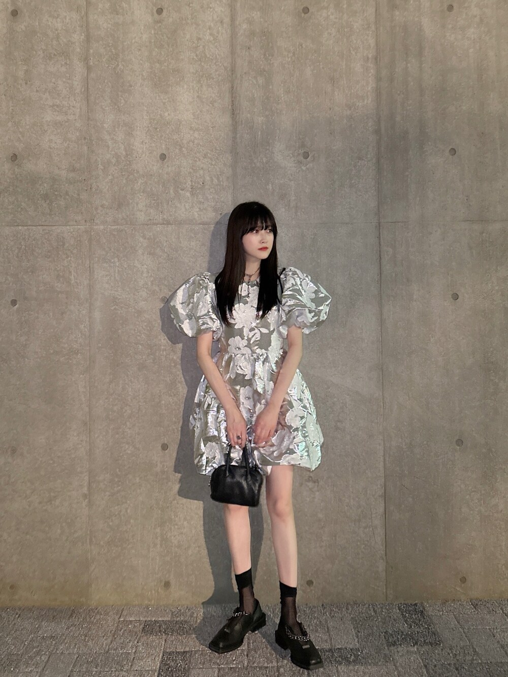 シルバー系のワンピース、ブラック系のローファー、ブラック系のハンドバッグを着用したレディースの夏コーディネートの2枚目の写真